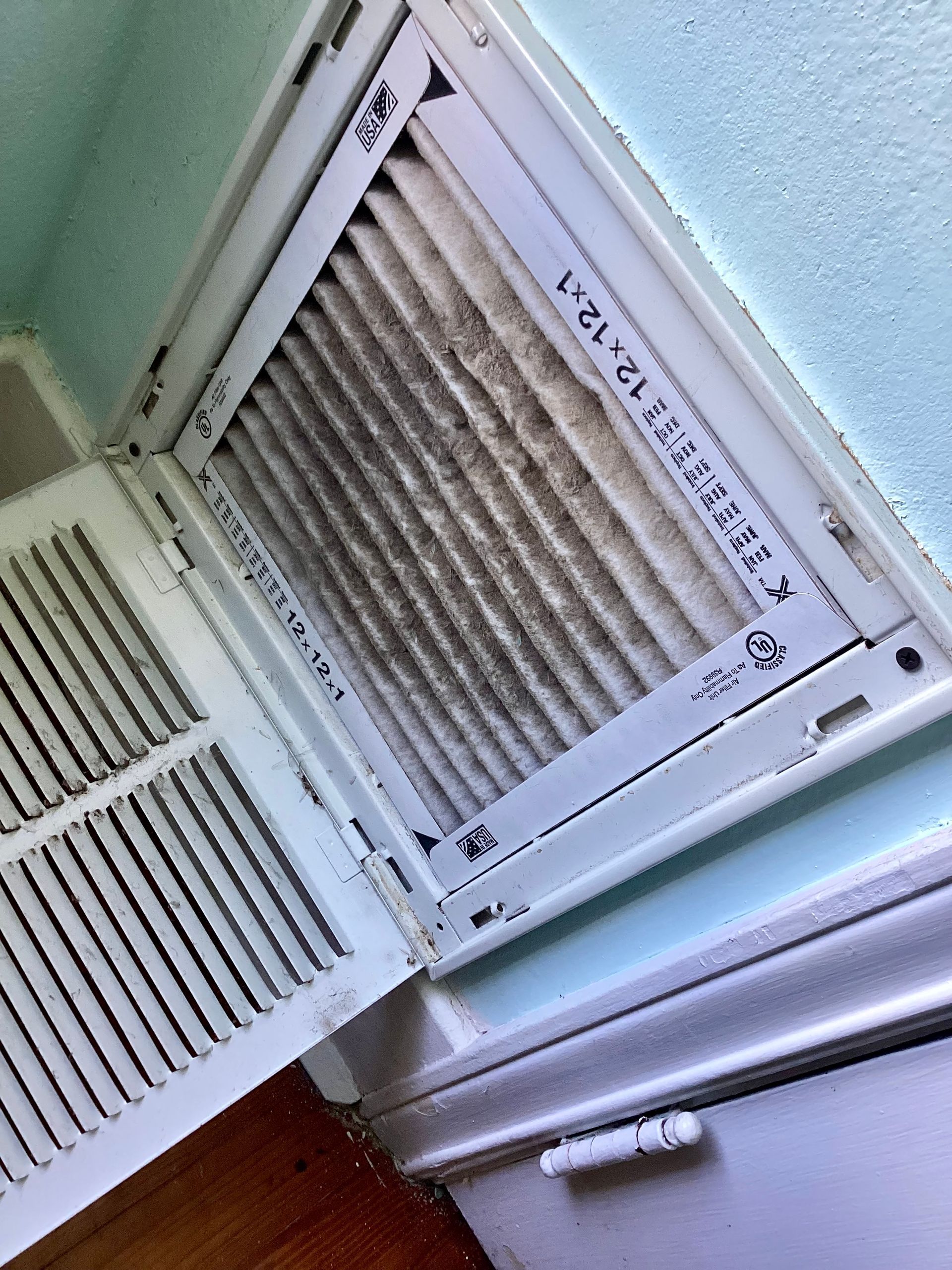 A close up of a dirty air filter on a wall.