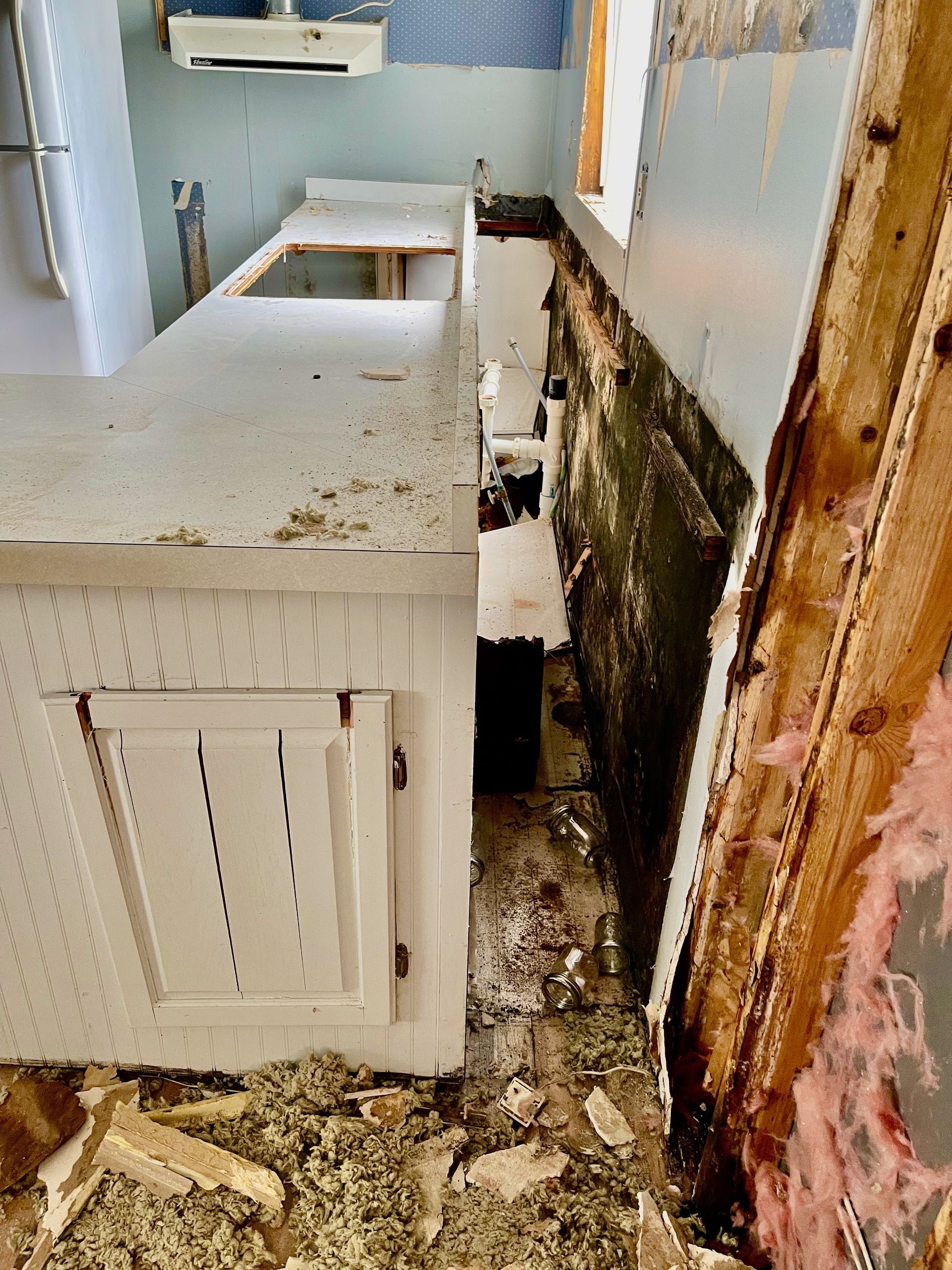 A kitchen with a broken counter top and a broken wall.