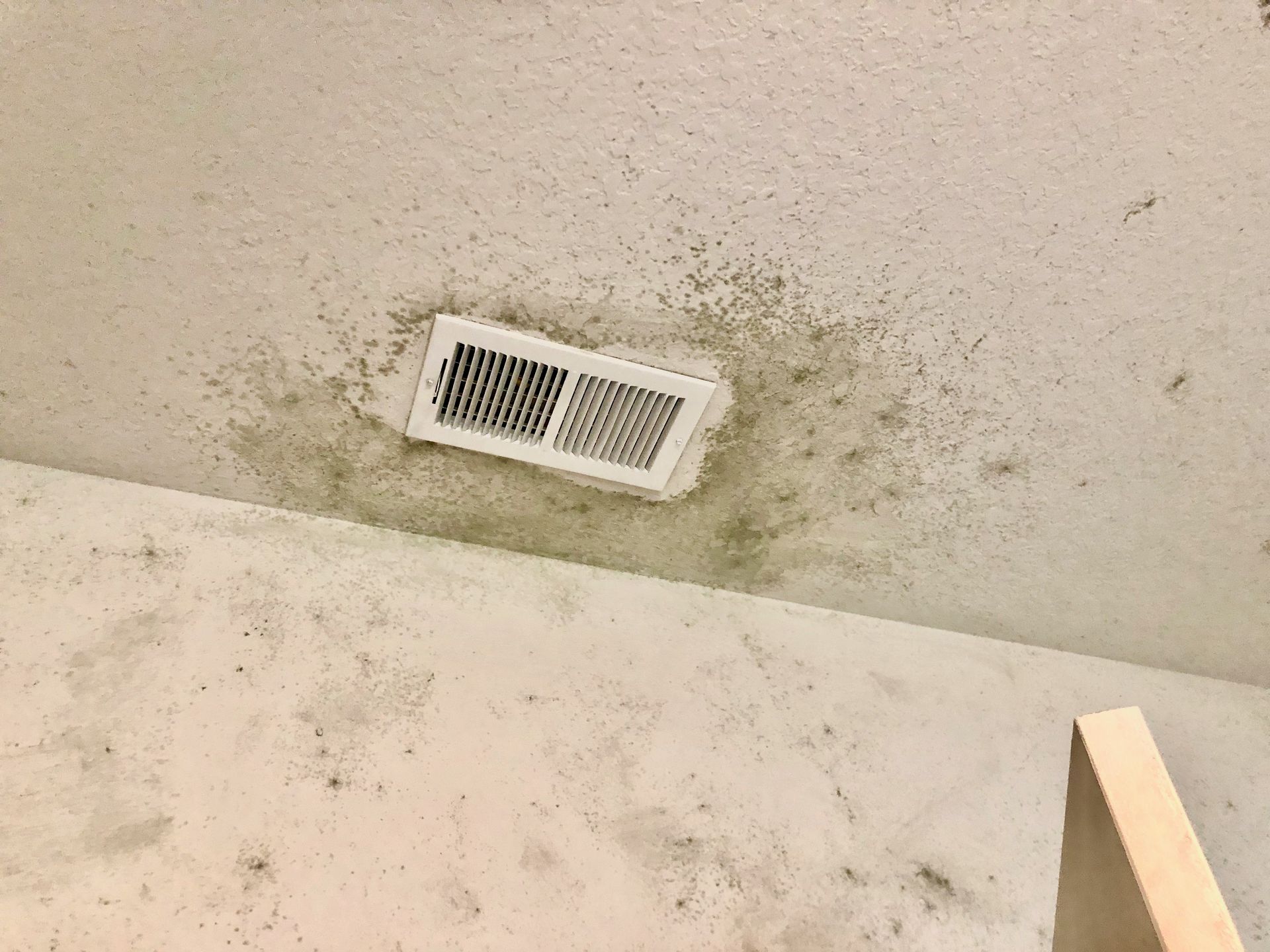 a dirty ceiling with a white vent on it