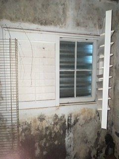 a white window is sitting on a moldywall next to a cage