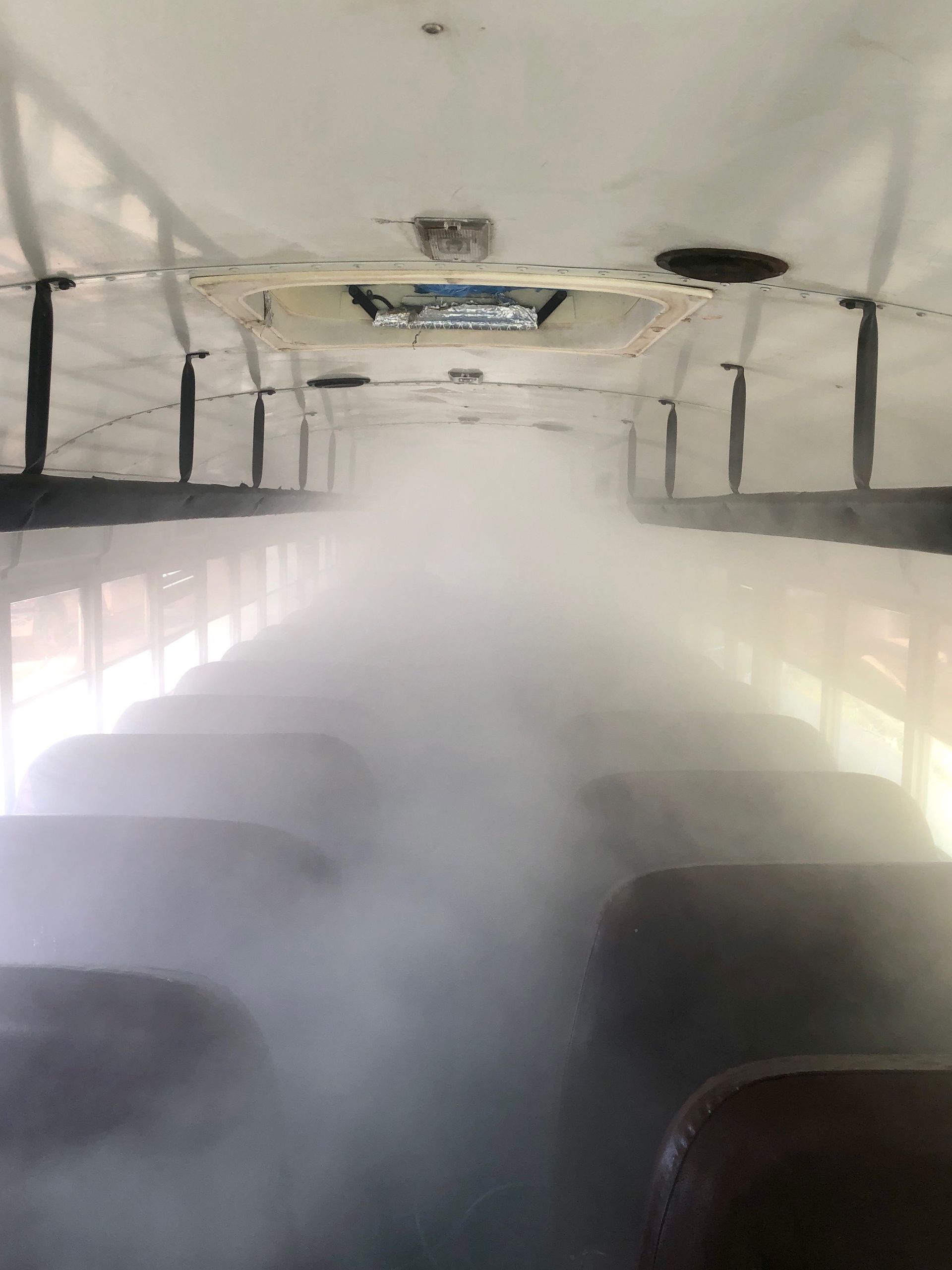 Interior of a school bus filled with thick fog, obscuring the seats and ceiling.