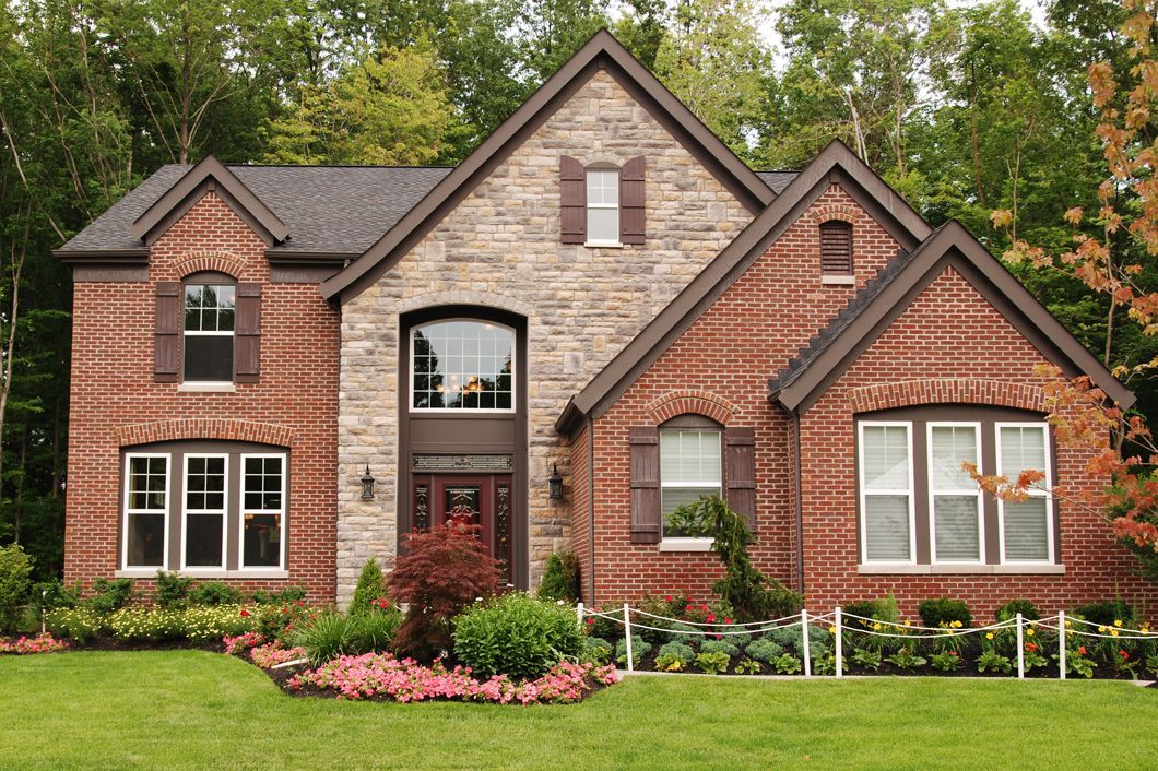 A large brick and stone house with a lush green lawn in front of it