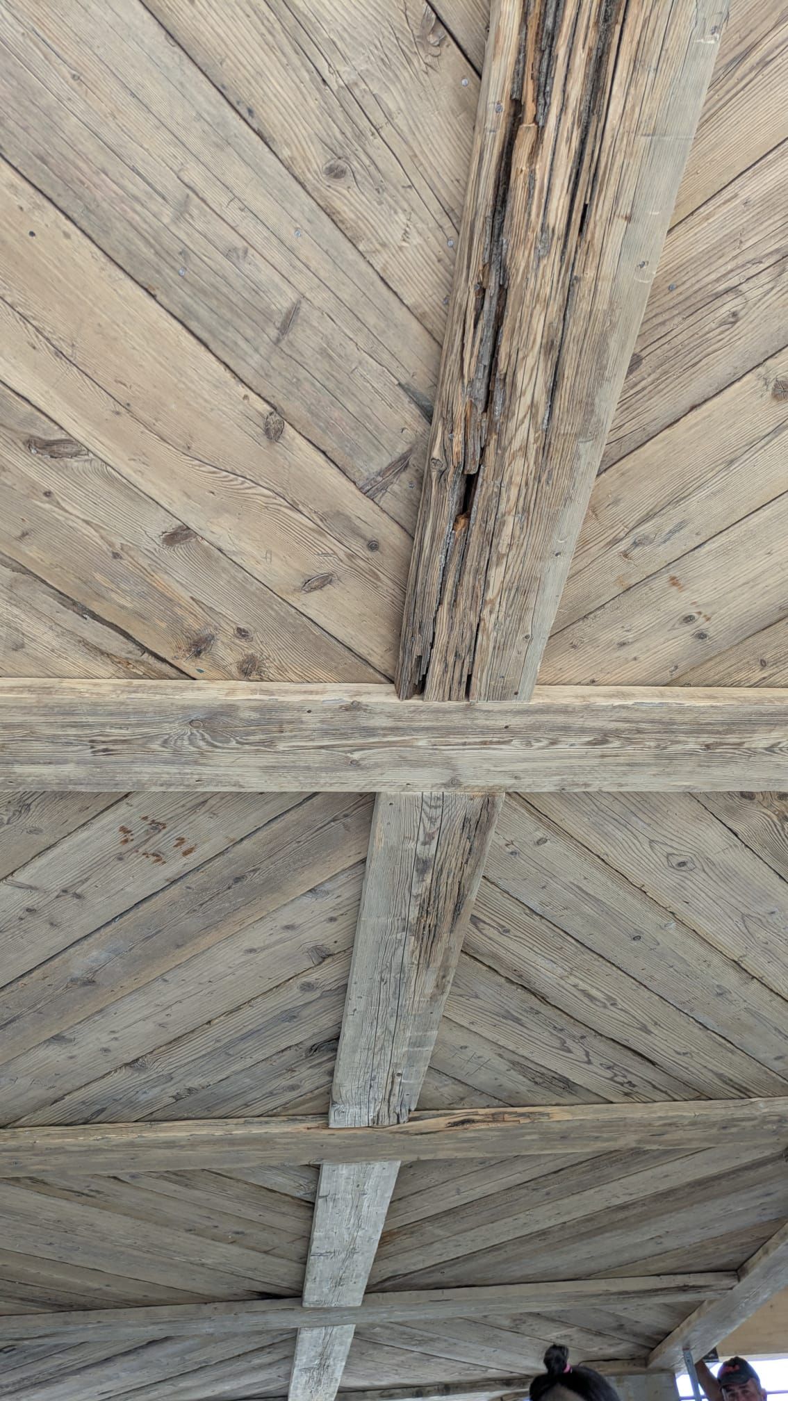 Soffitto in legno con travi disposte in diagonale, invecchiato e grigio.