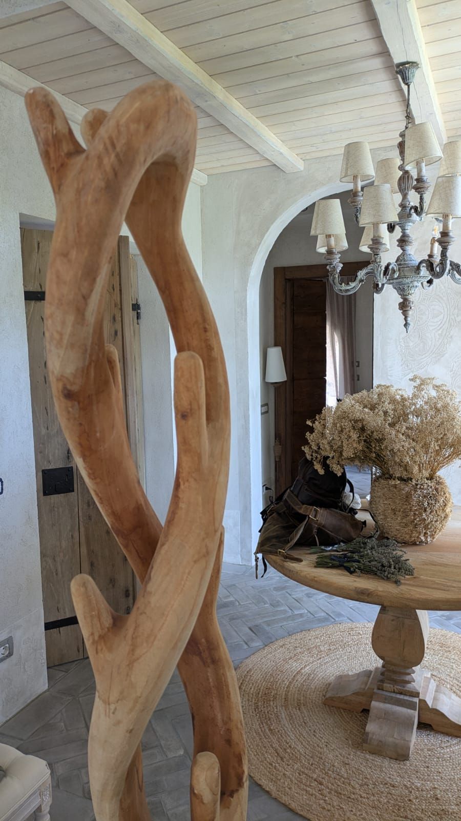Scultura in legno da interno con tavolo rotondo, lampadario e arco.