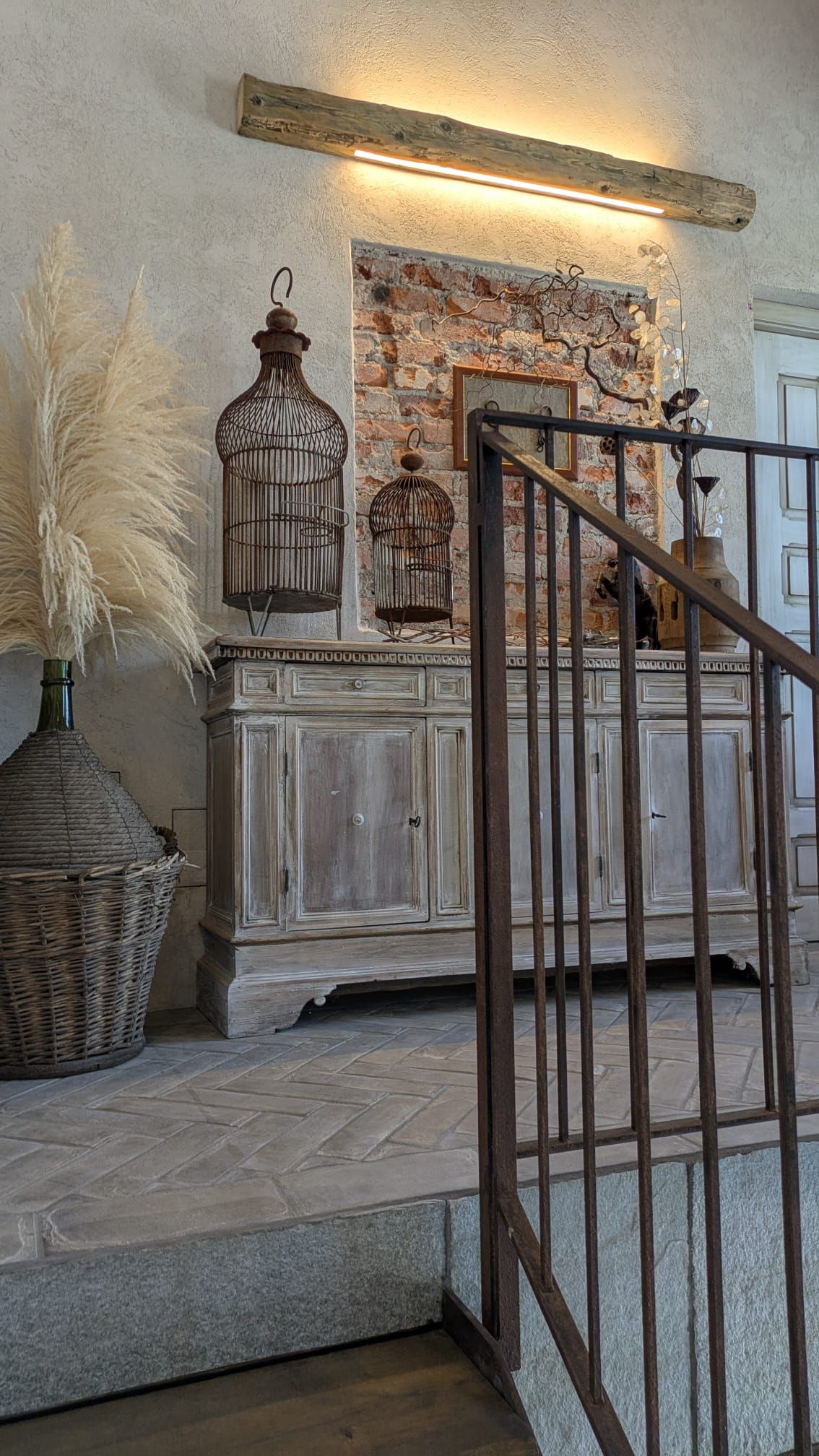 Mobile rustico con gabbie per uccelli, sfondo in mattoni e ringhiera per scale.