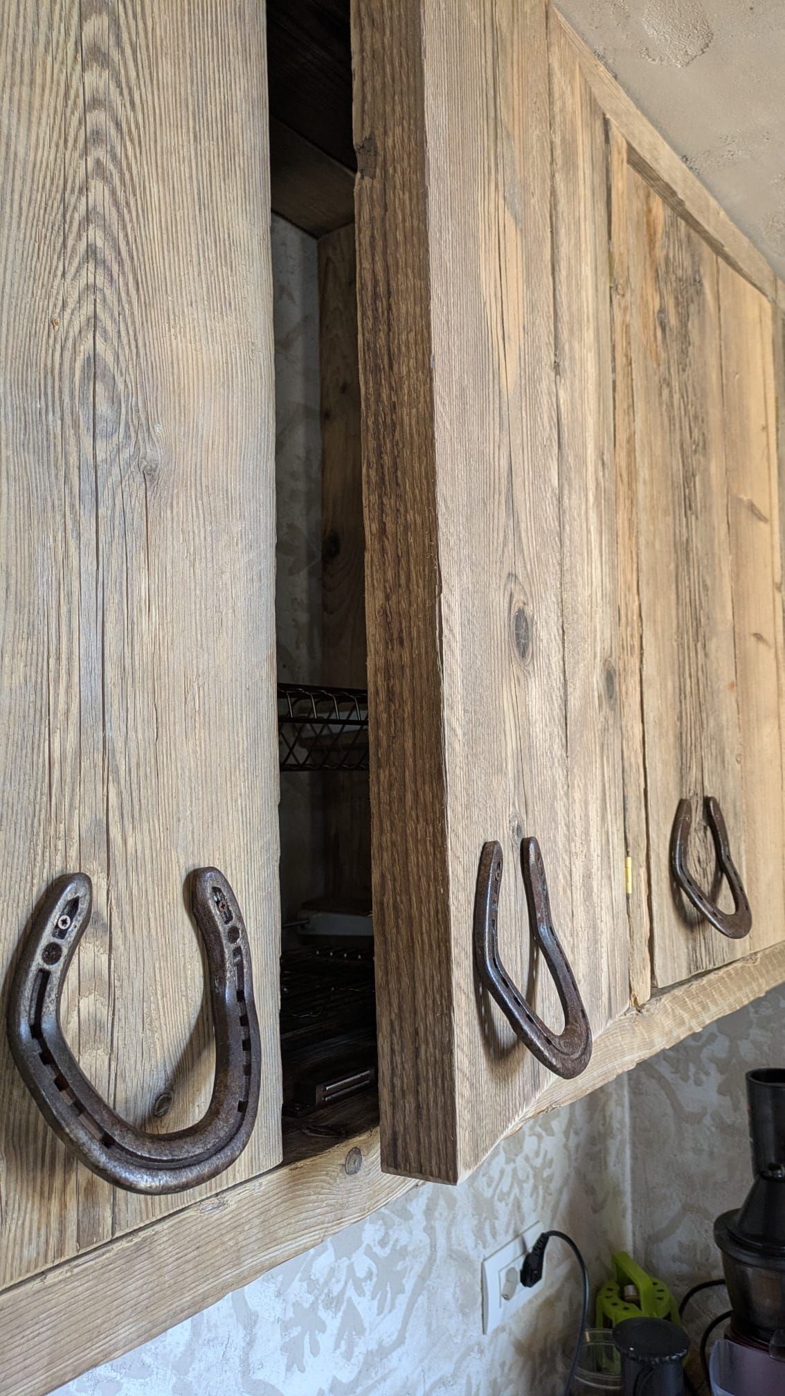 Mobili da cucina in legno rustico con maniglie a ferro di cavallo, un mobile aperto.