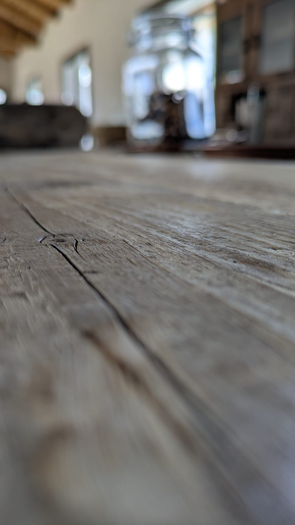 Primo piano di una superficie in legno usurata, profondità di campo ridotta con sfondo interno sfocato.