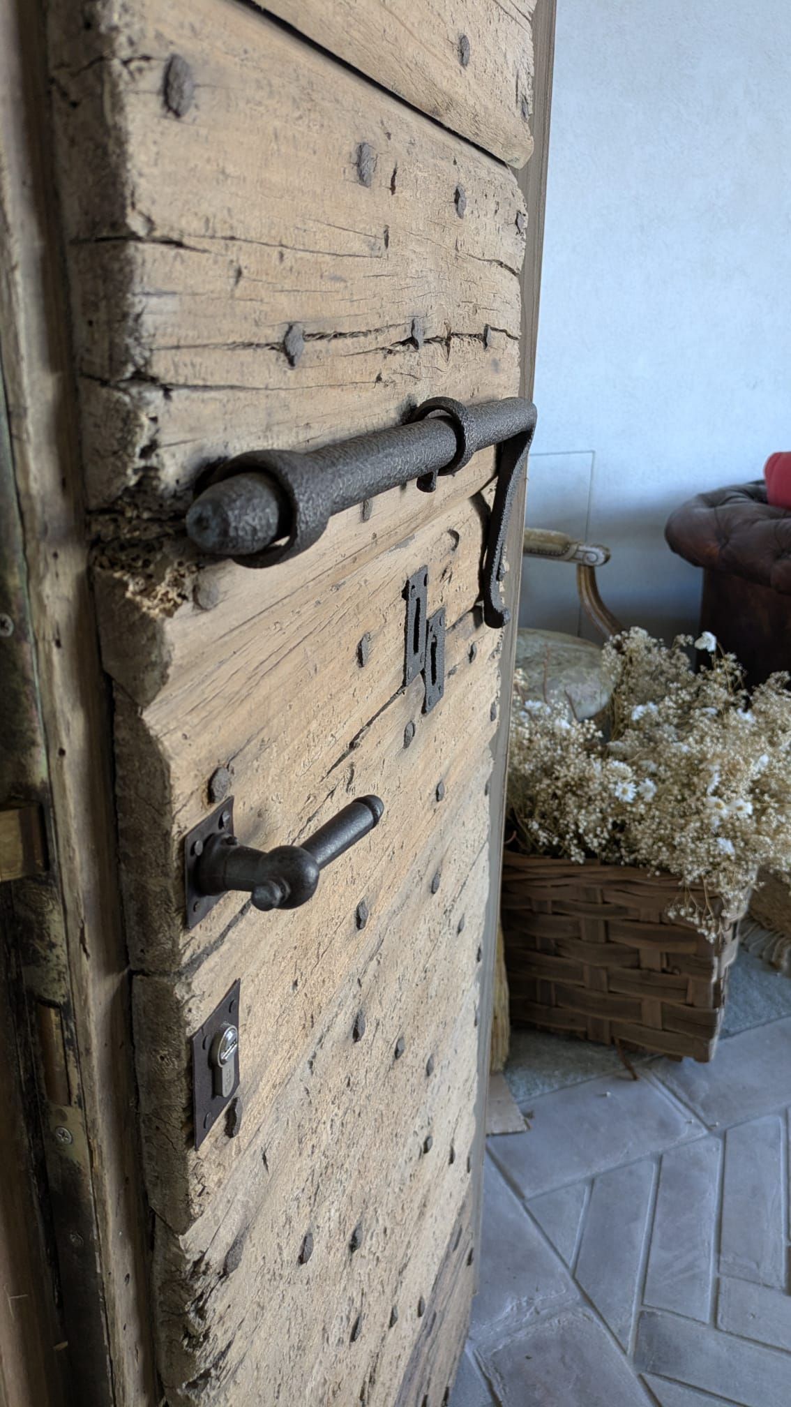 Porta in legno con grande barra metallica e maniglia; interno decorato con fiori.
