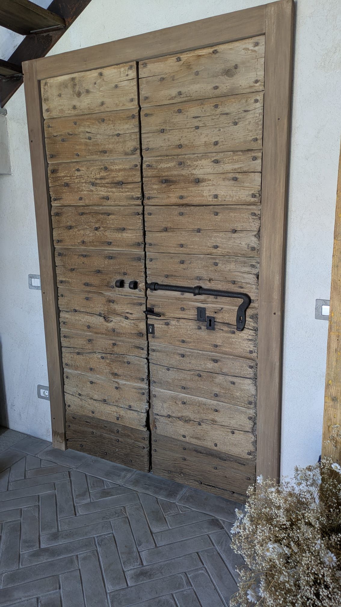 Doppie porte in legno con ferramenta in metallo scuro in un ambiente rustico.