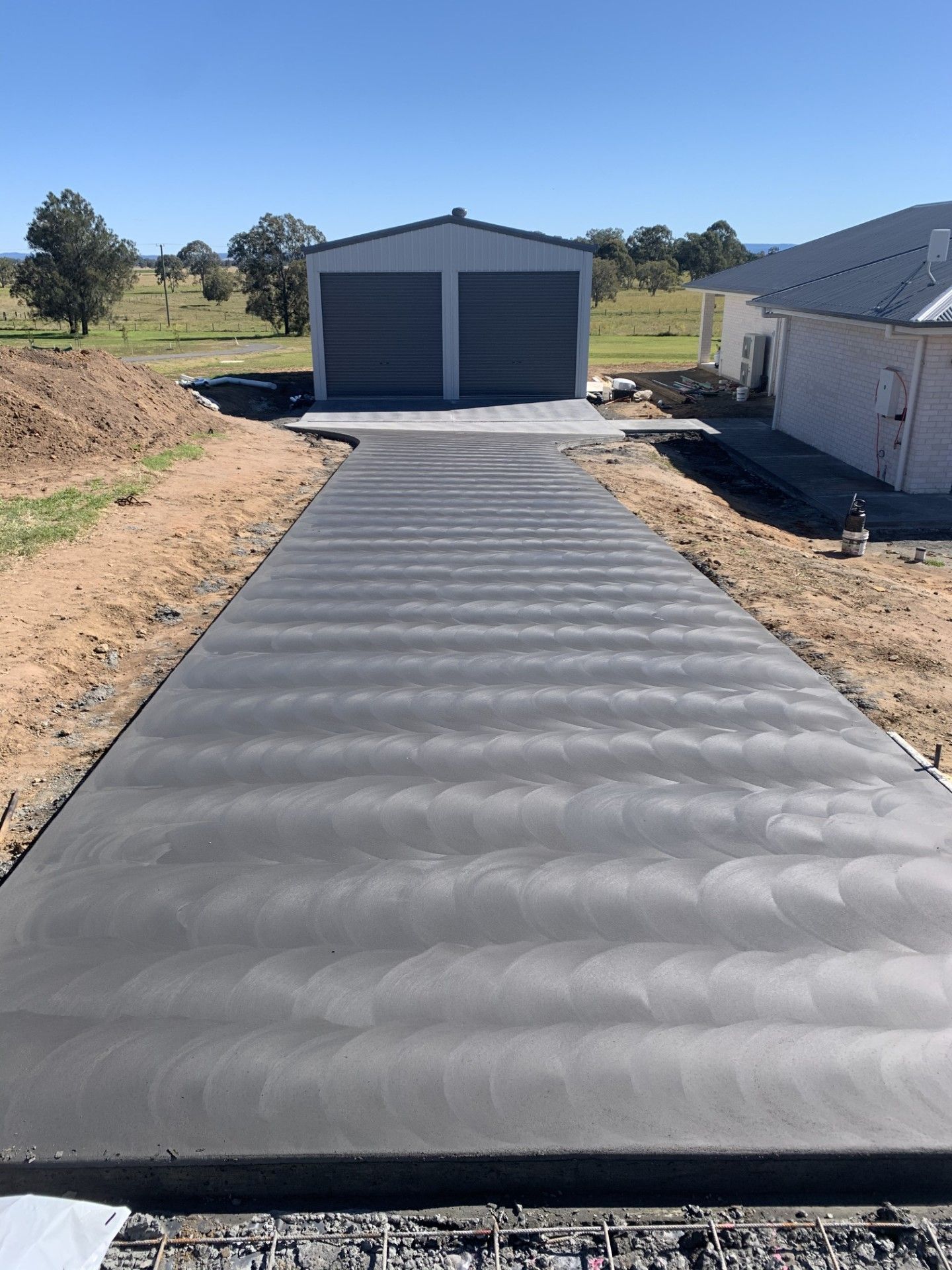 A long decorative driveway leading to a shed — Wal's Concreting Service in Byron Bay, NSW