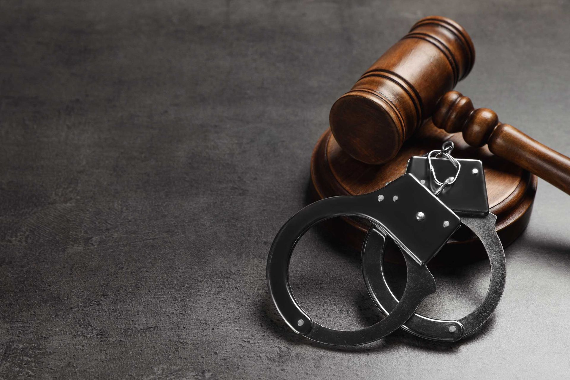 Closeup to handcuffs on a wooden gavel, representing criminal law.