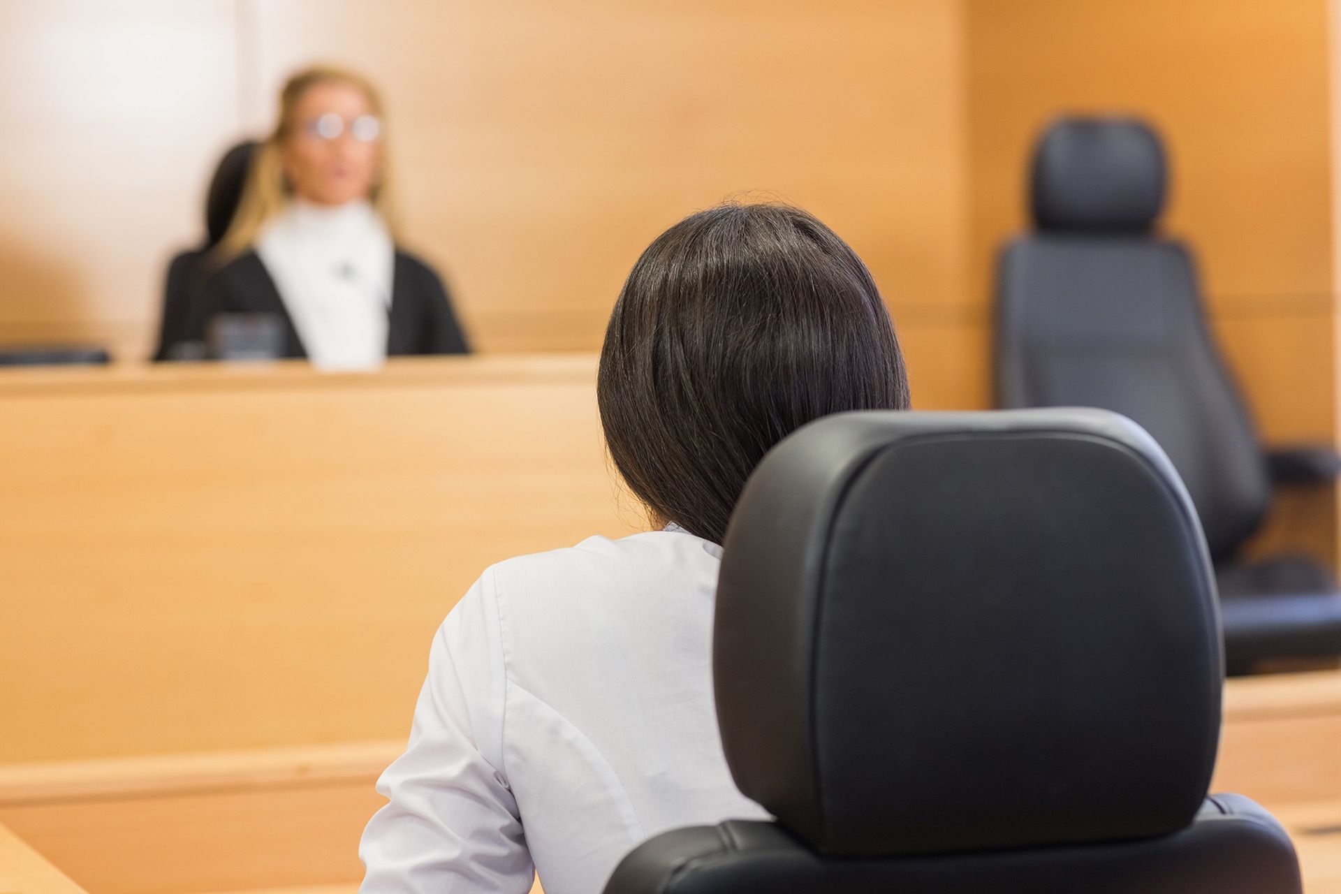 A rear view of a lawyer listening to a judge in a court room.