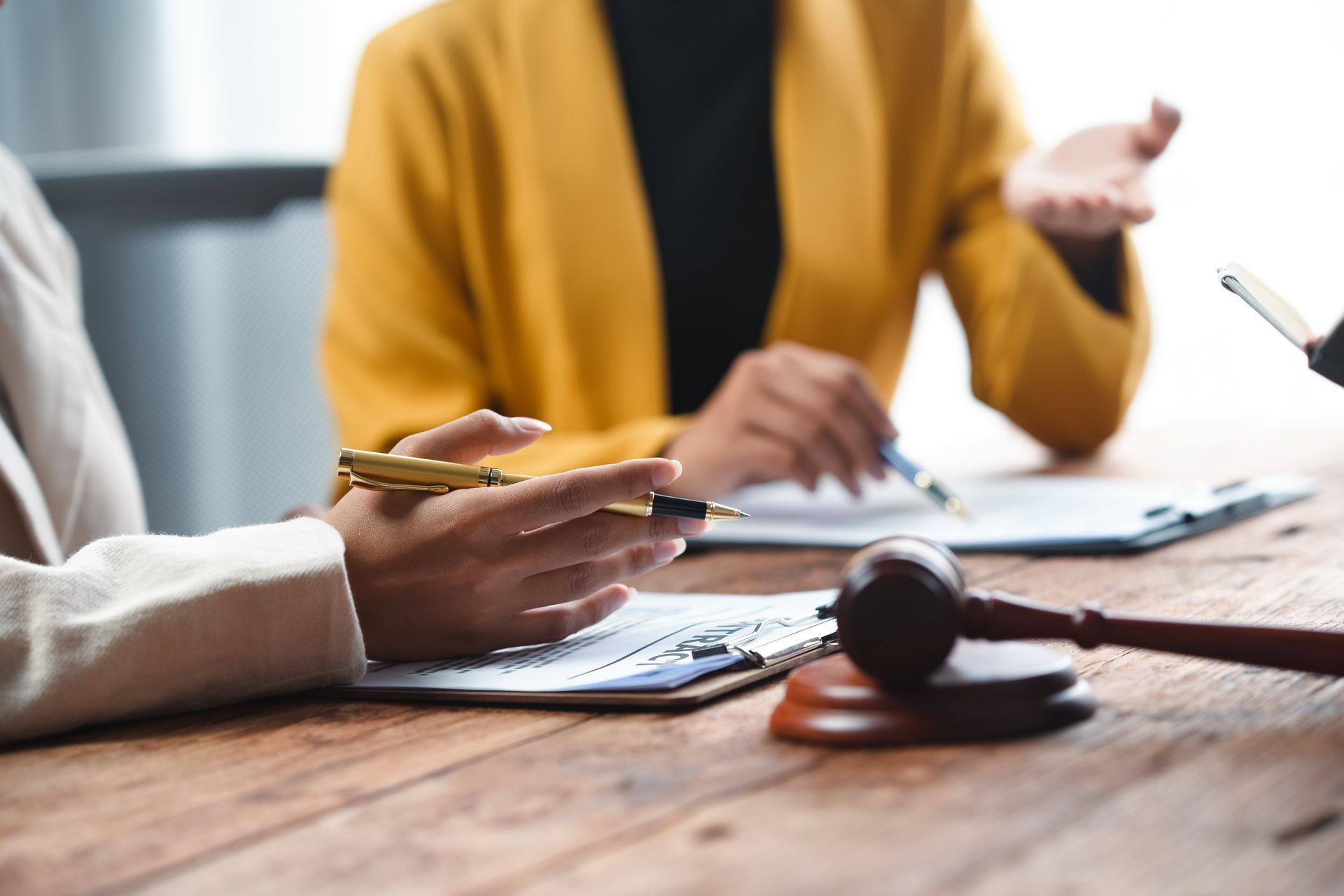 A partial view of three lawyers discussing documents with a gavel on a table.