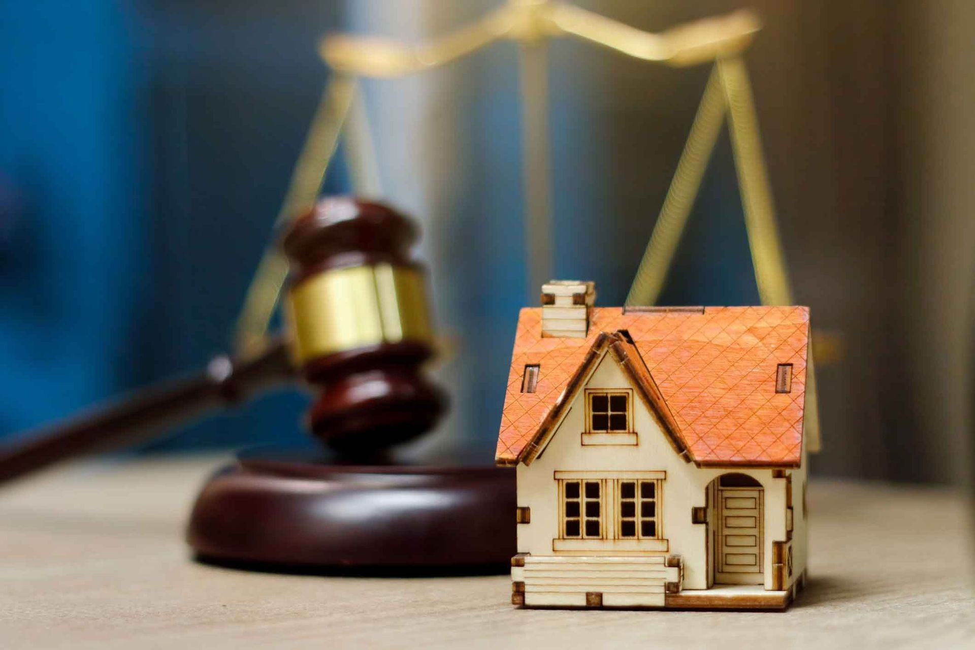 A small wooden house is sitting on a table in front of a judge 's gavel.