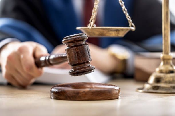 A judge's gavel striking a sound block with scales of justice in the background.