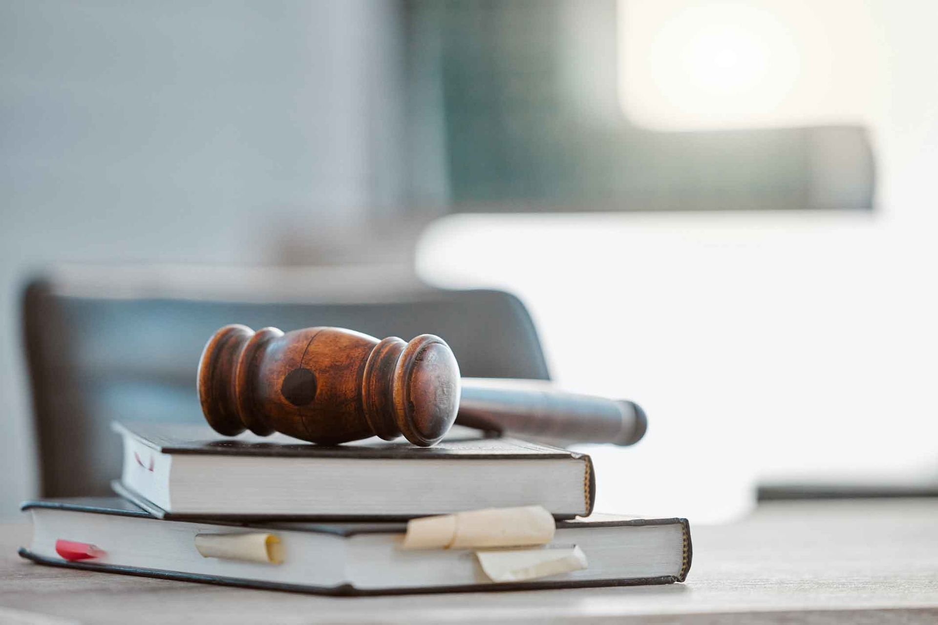A wooden judge 's gavel is sitting on top of a stack of books.