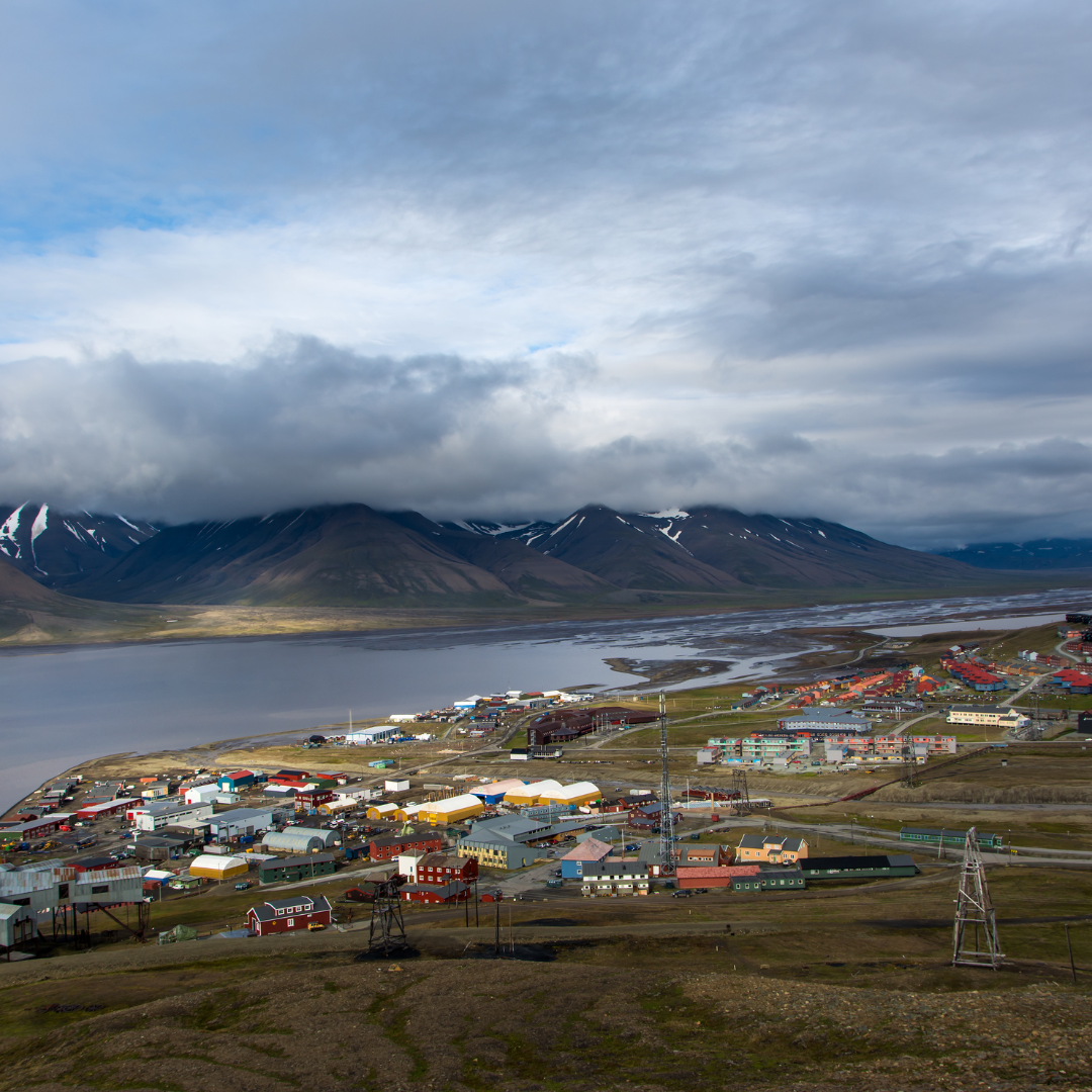An aerial view of a small town next to a lake with mountains in the background.