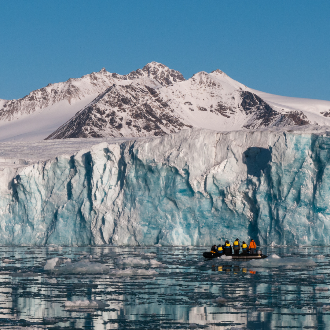 A group of people in a boat in front of a glacier