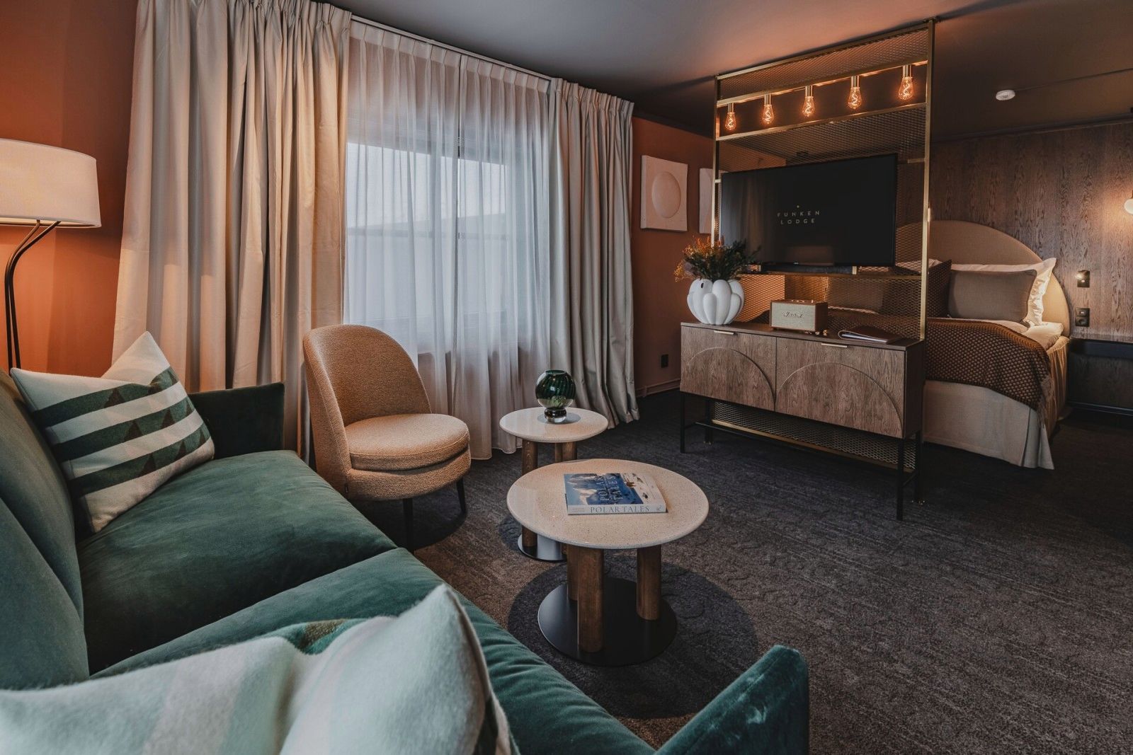 A hotel room with a couch , chair , table and television.