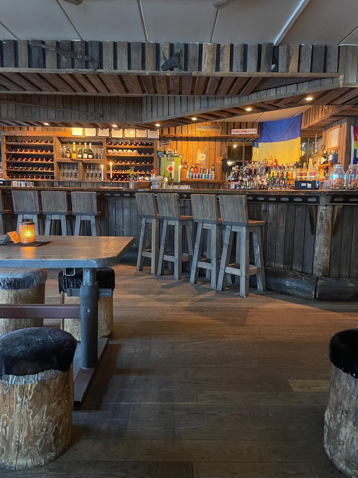 A restaurant with wooden tables , chairs , barrels and a bar.