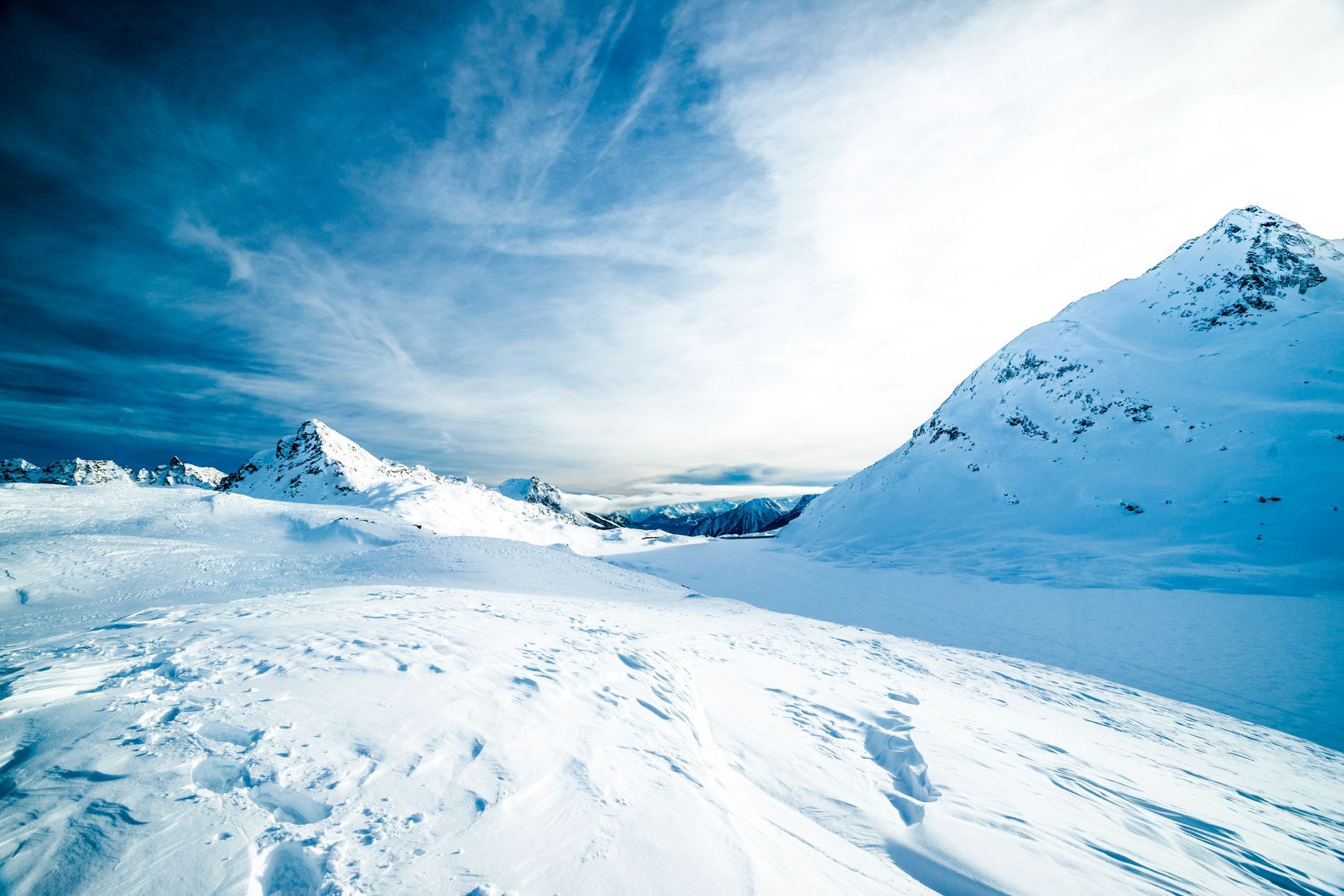 A snowy mountain covered in snow with a blue sky in the background.