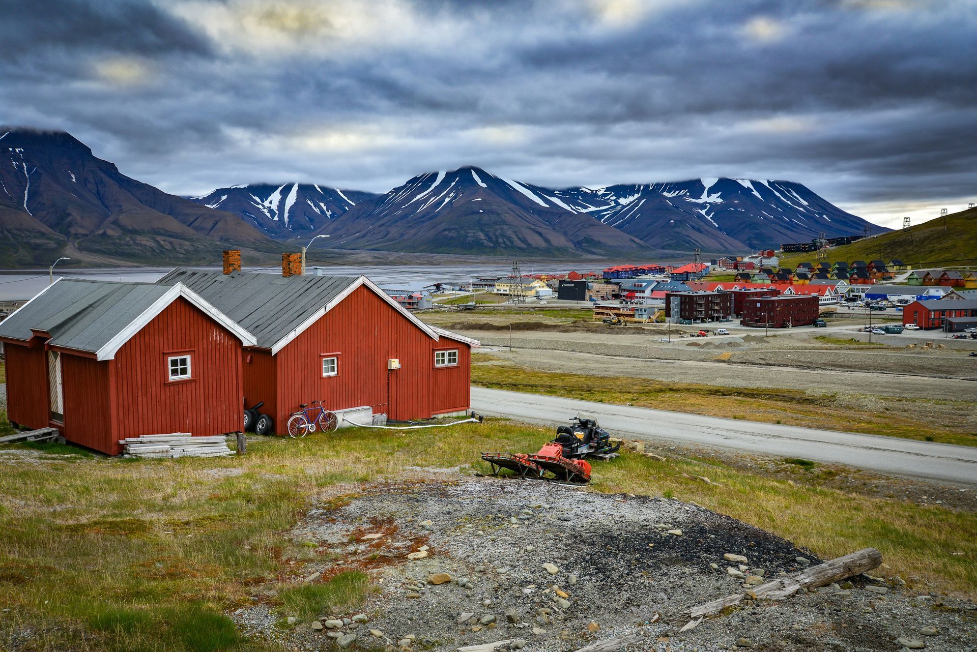 A row of red houses with mountains in the background.
