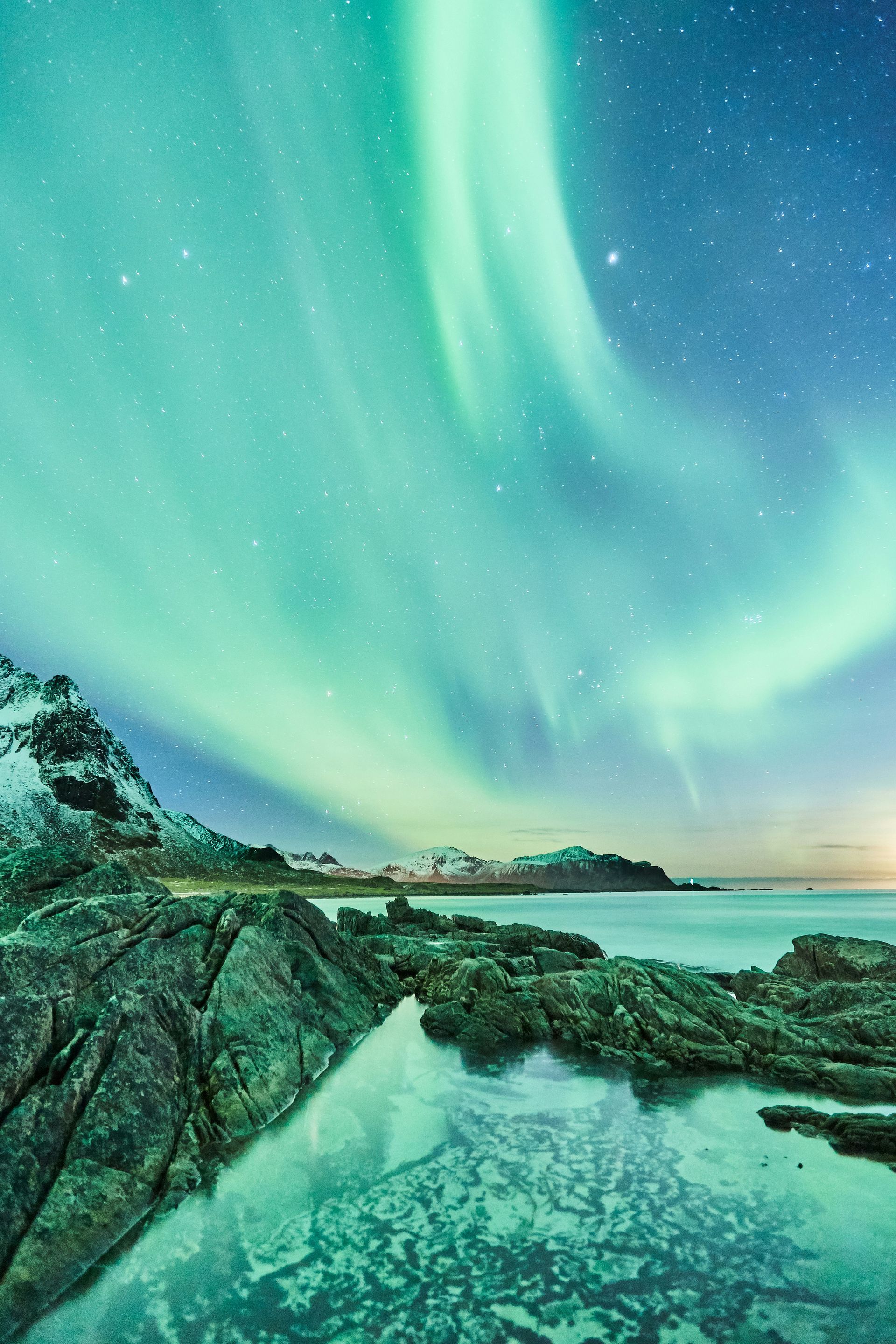 The northern lights are dancing in the sky over a body of water.