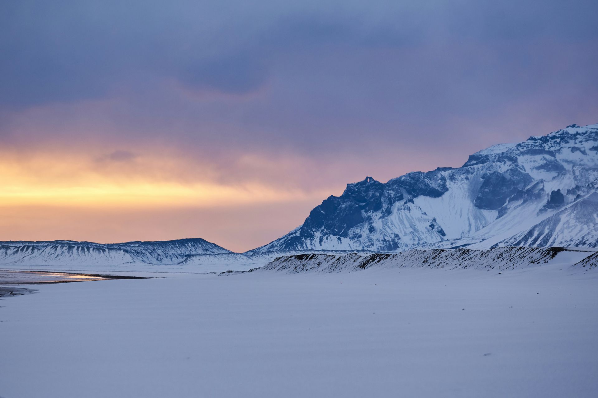 A snowy mountain range with a sunset in the background