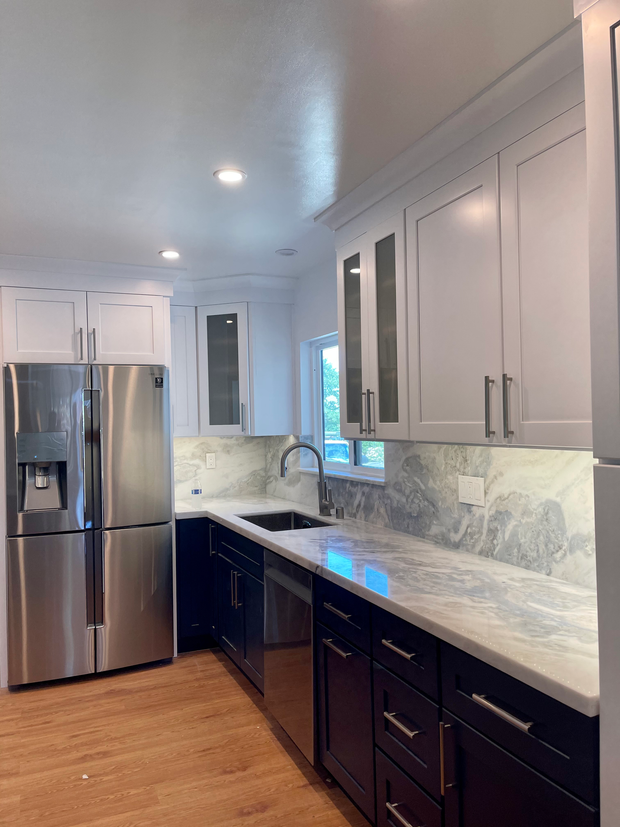 Modern kitchen with white cabinets, stainless steel appliances, and dark cabinets.