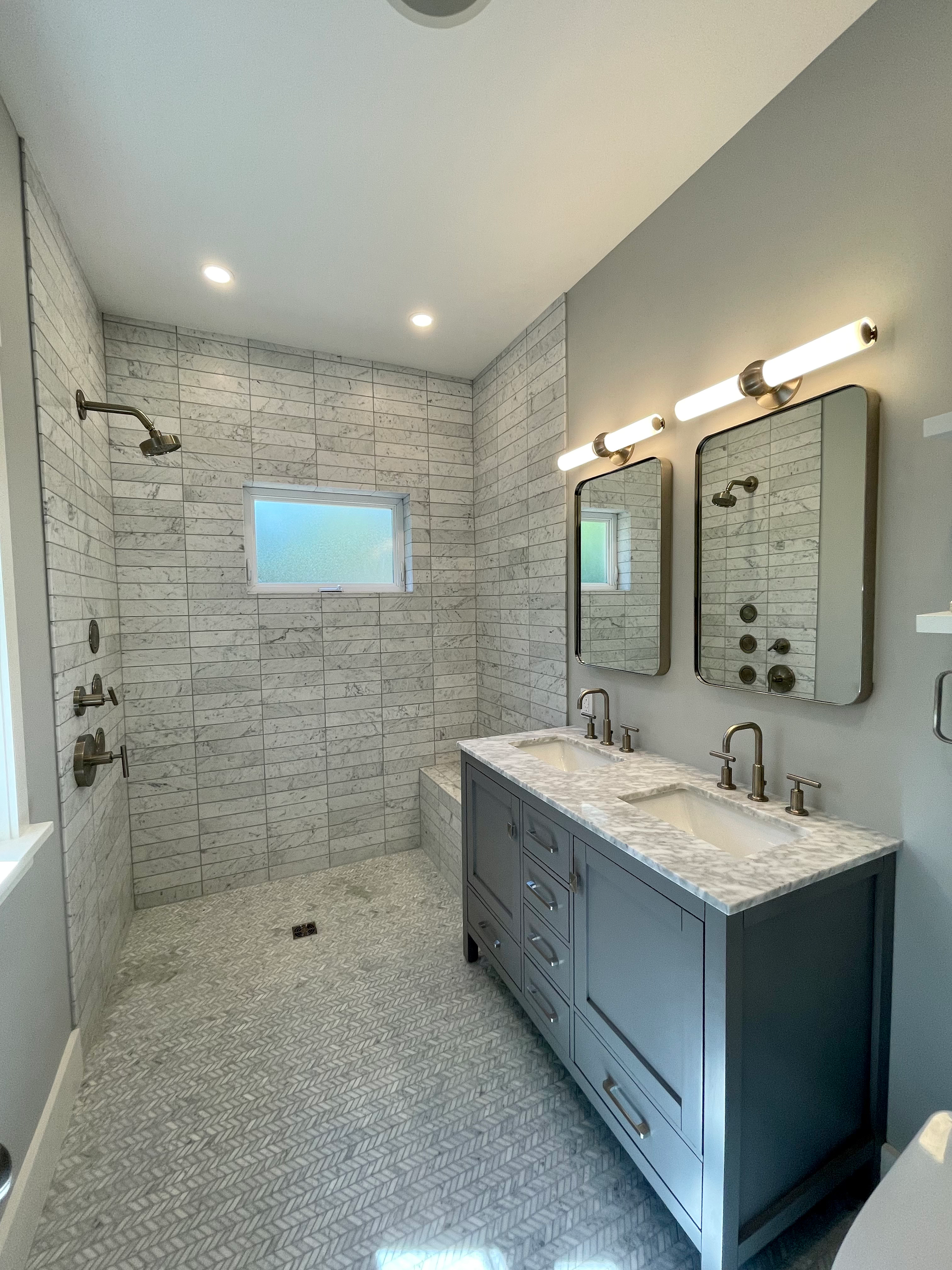 Modern bathroom with gray and white tile, double vanity, and shower.