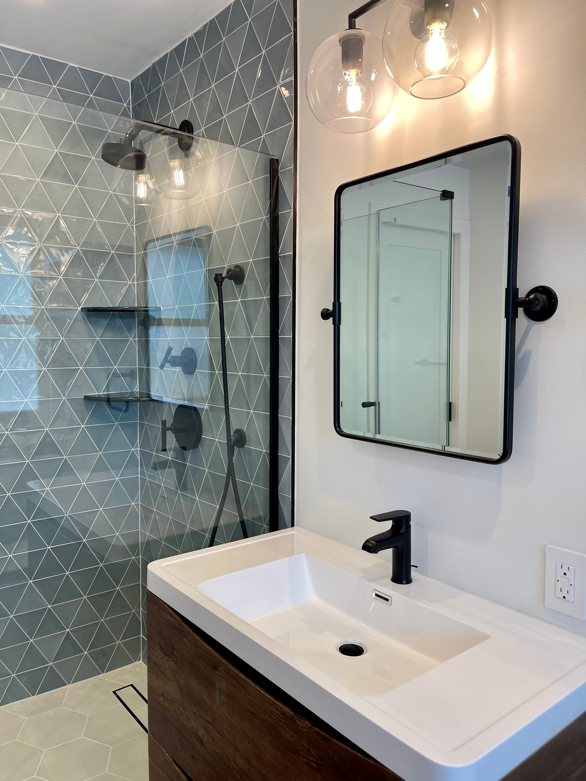Bathroom with a white sink, black fixtures, and a shower with patterned blue tile.