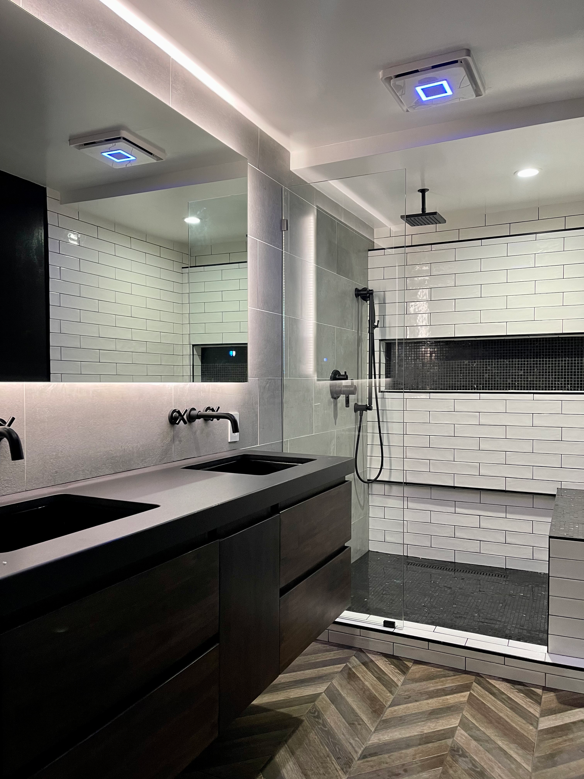 Modern bathroom with dark vanity, white textured walls, and glass shower.