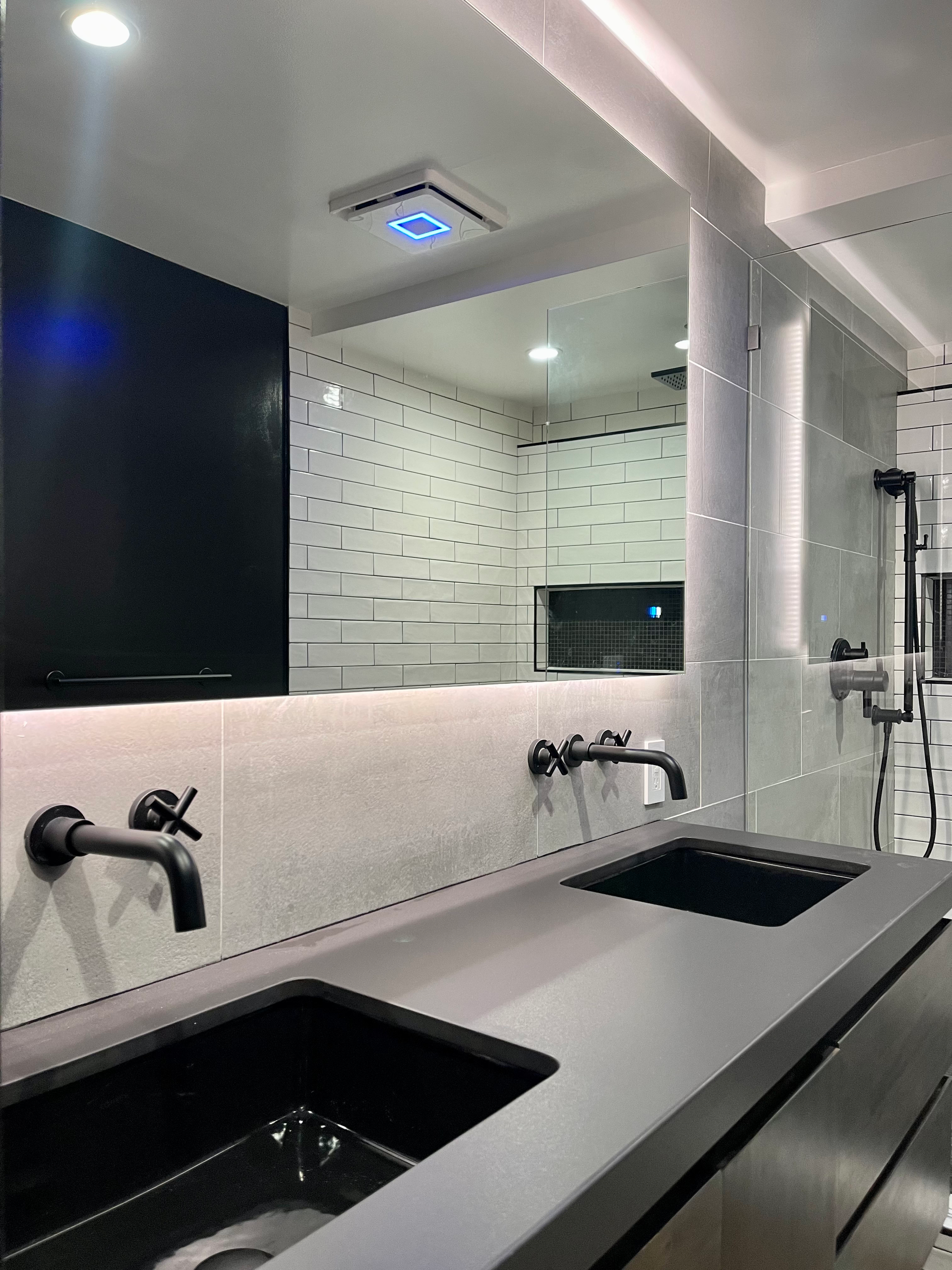 Modern bathroom with black sinks, faucets, and accents, large mirror.