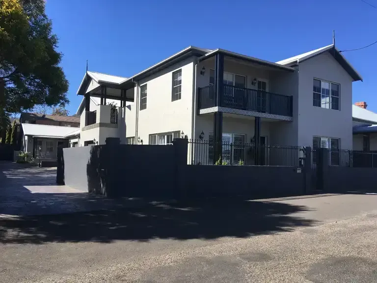A Large White House With A Black Fence In Front Of It — Tamworth Strata Management Services in Tamworth, NSW