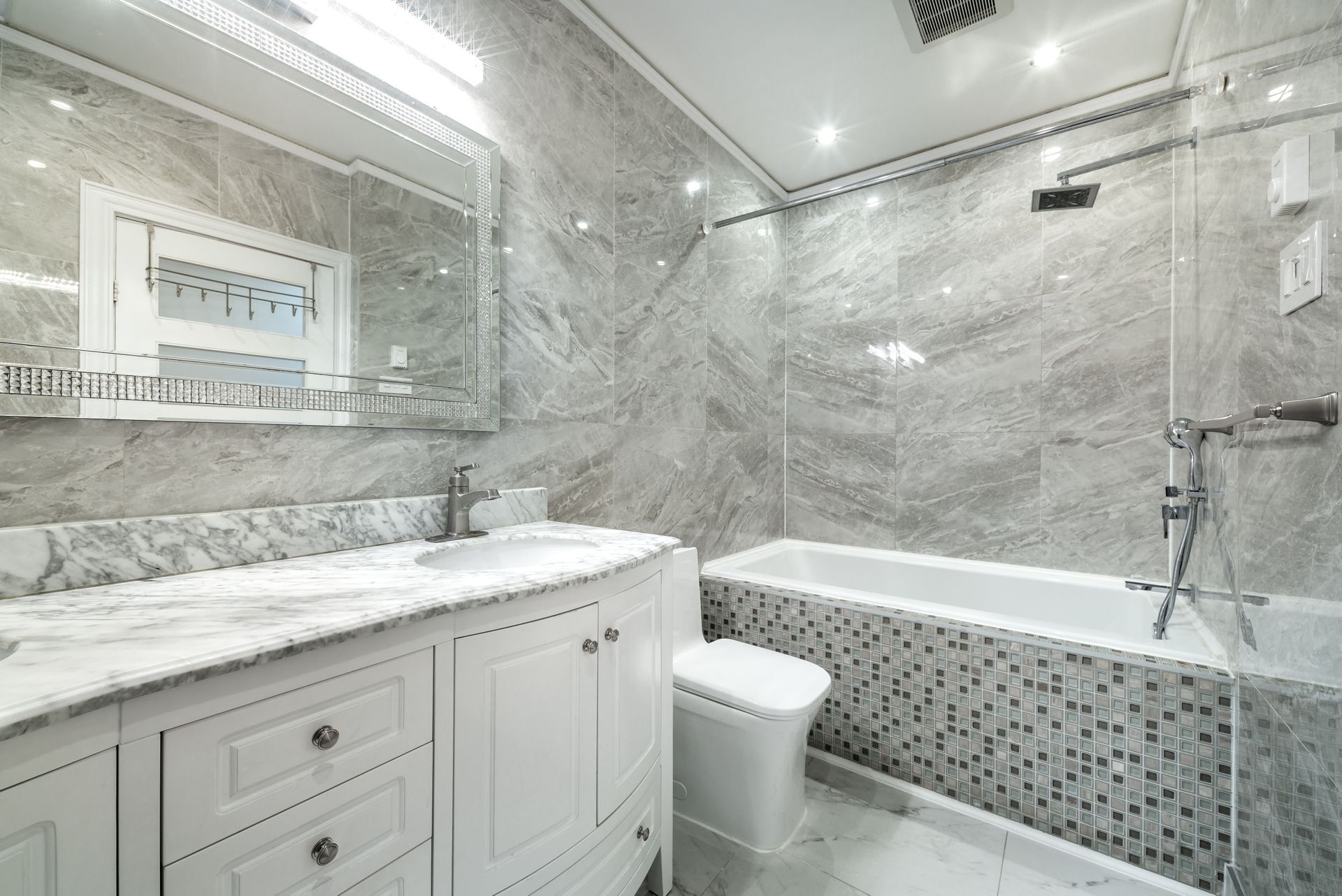 A bathroom with a tub , sink , toilet and mirror.