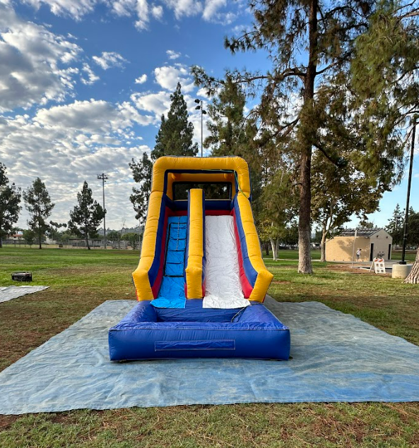 A blue and yellow inflatable water slide in a park