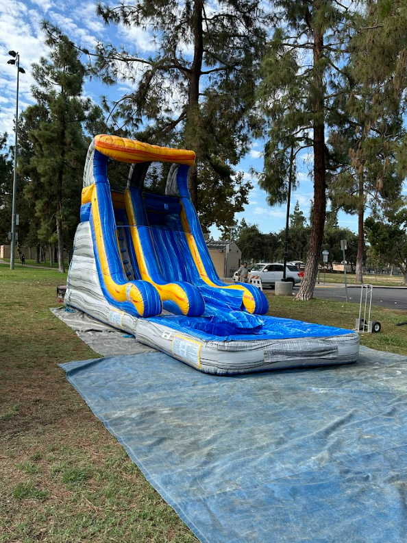 A large inflatable water slide is sitting on top of a tarp in a park.