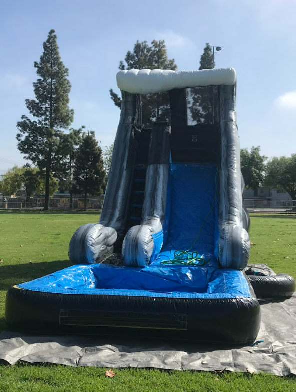 A large inflatable water slide is sitting on top of a lush green field.