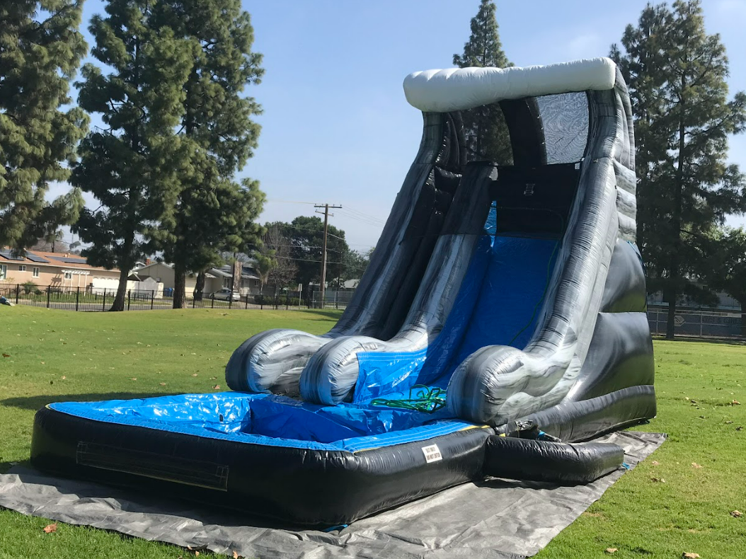 A large inflatable water slide is sitting on top of a lush green field.