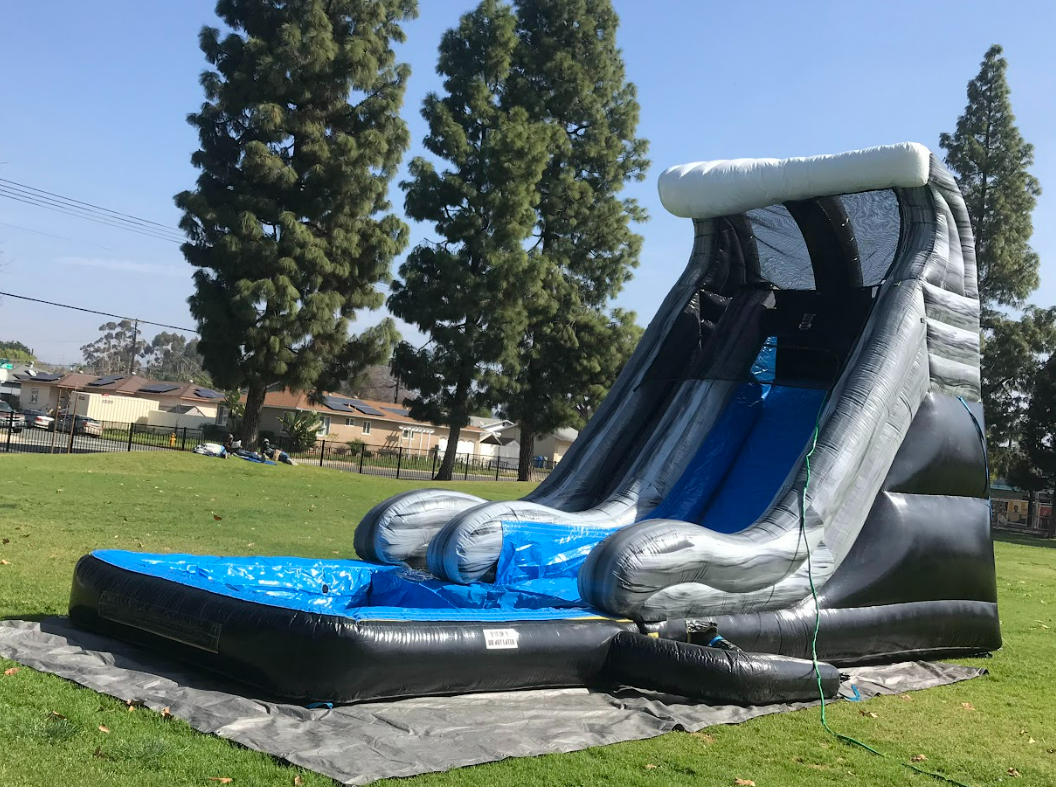 A large inflatable water slide is sitting on top of a lush green field.
