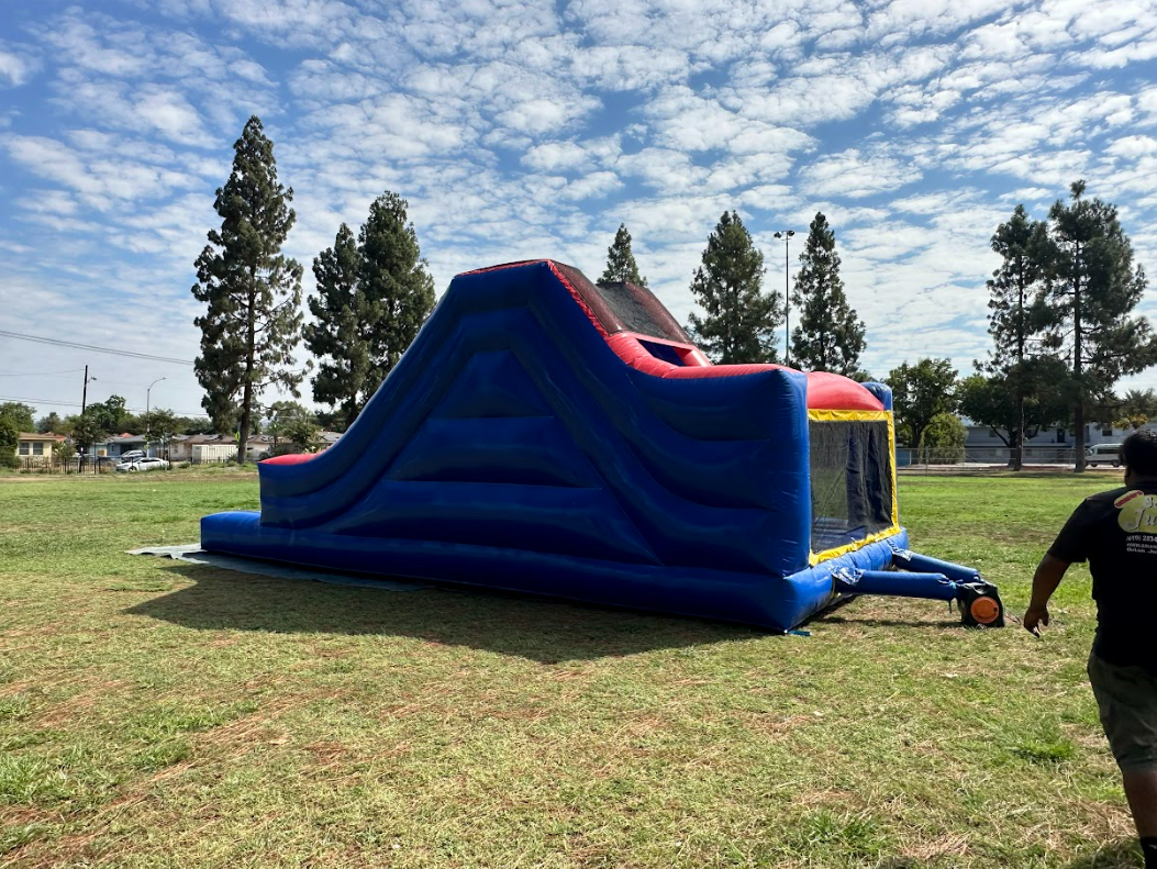 A man is walking towards a bouncy house in a field.