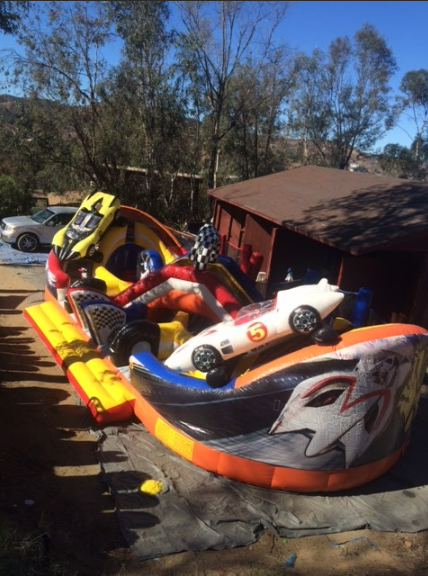 A bunch of inflatable cars are sitting in front of a house