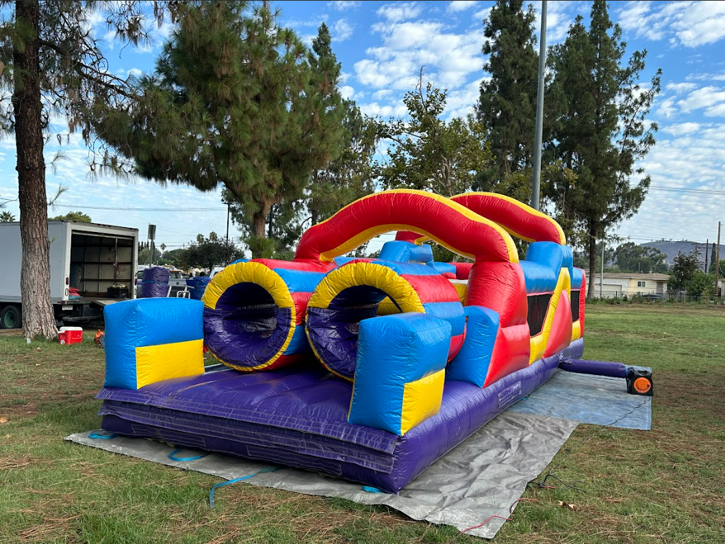 A large inflatable obstacle course is sitting on top of a blanket in a park.
