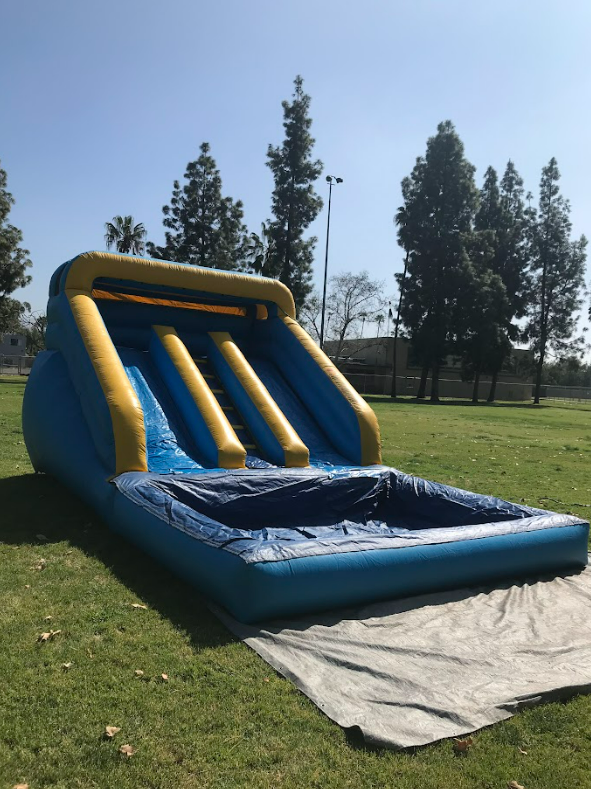 An inflatable water slide is sitting on the grass in a park.