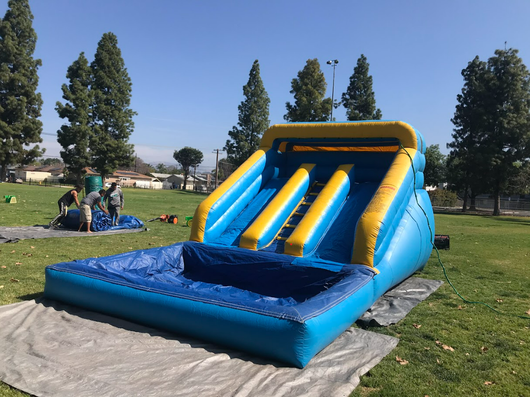 A large inflatable water slide is sitting on top of a blanket in a park.