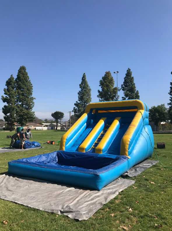 A large inflatable water slide is sitting on the grass in a park.