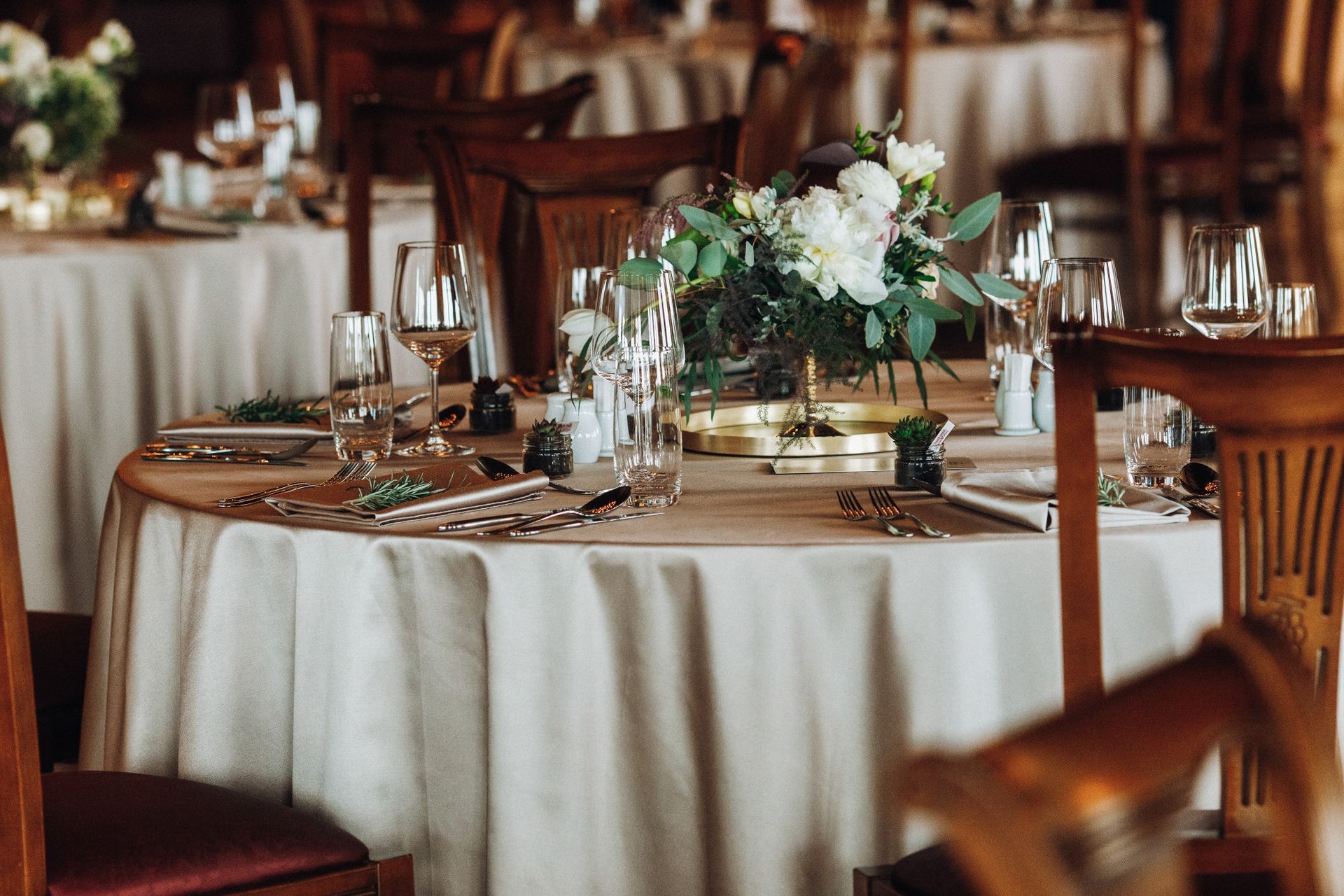A table set for a wedding reception with a vase of flowers on it.