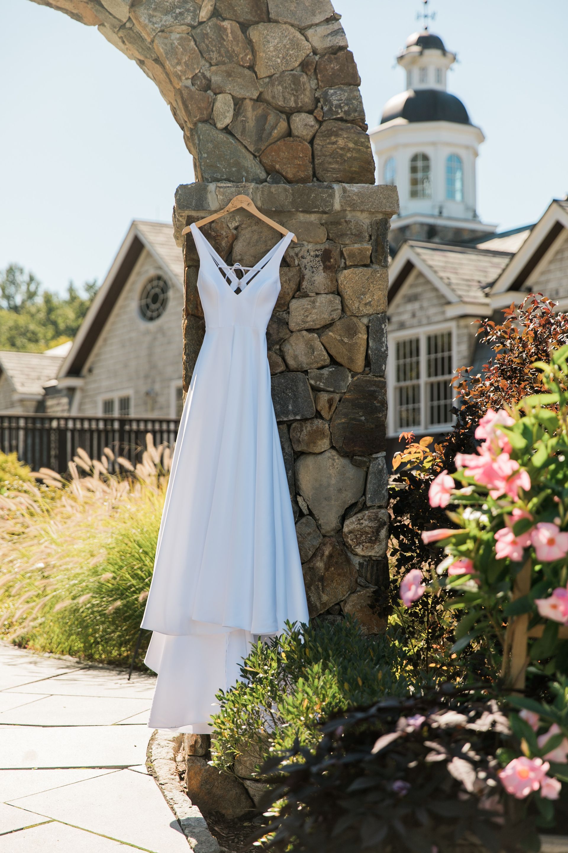 A white wedding dress is hanging on a stone archway.