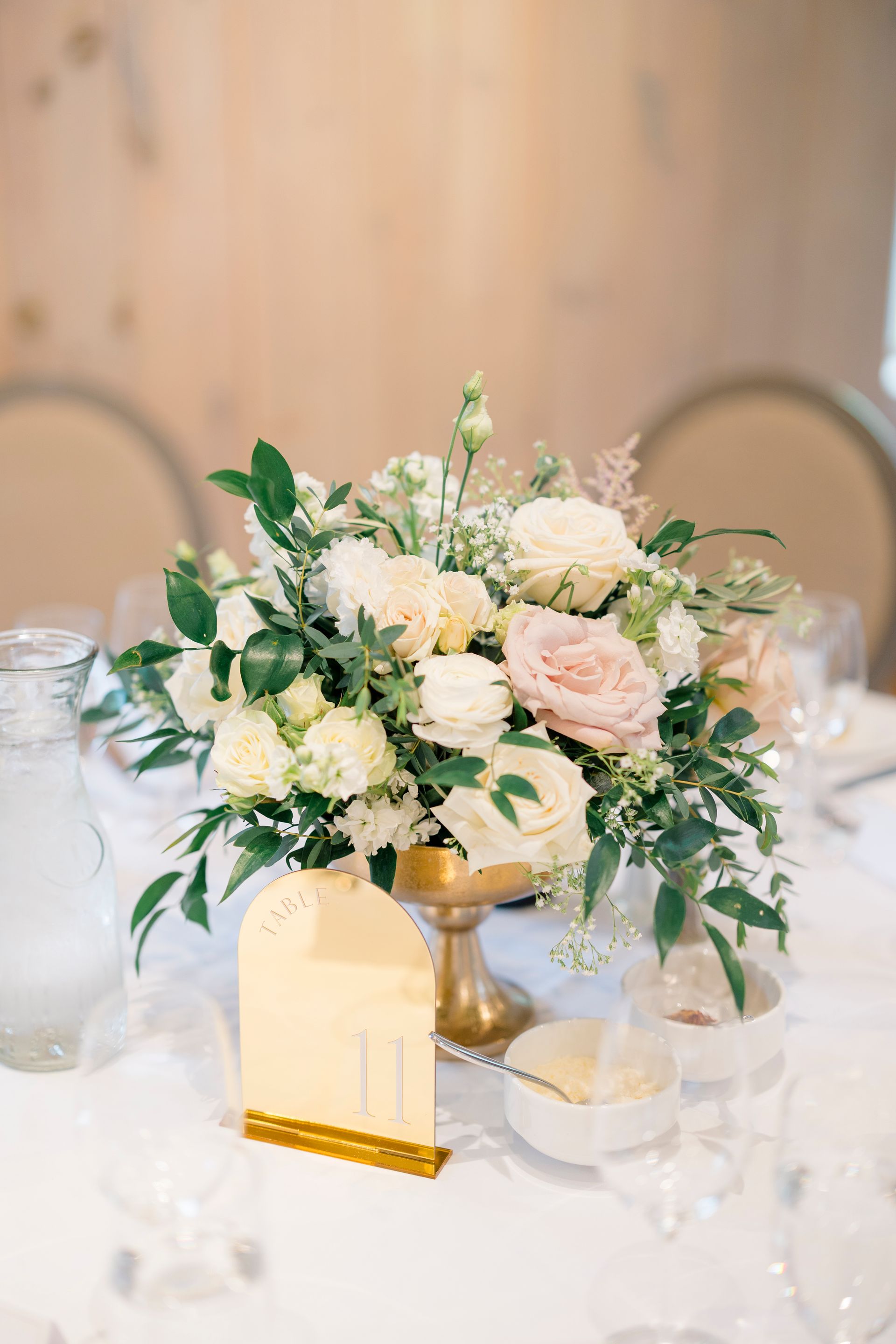A table with a vase of water and candles on it.