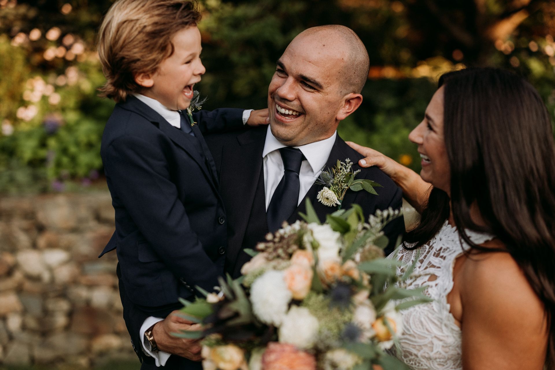 A bride and groom are posing for a picture with their son on their wedding day.